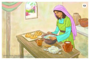 A woman stands at a table working some dough and yeast.